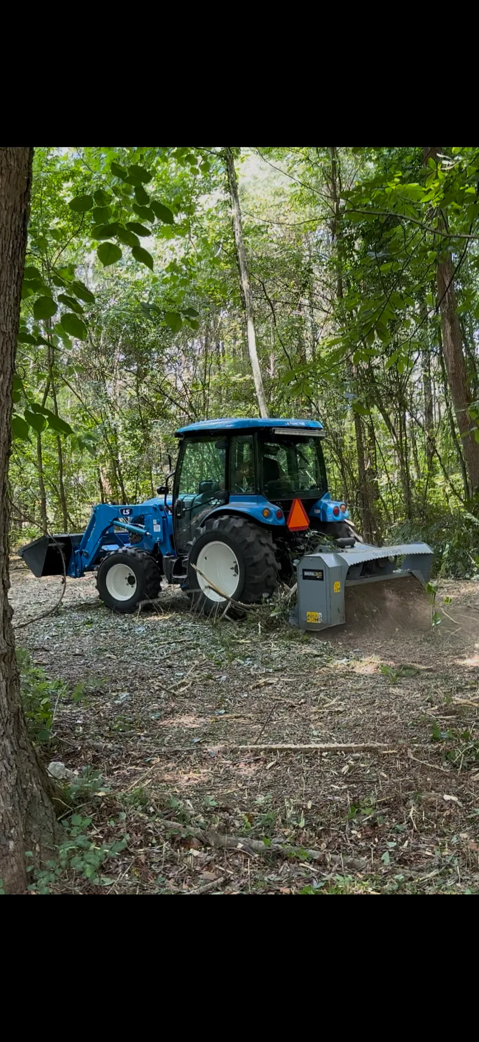 LS tractor with Baumalight forestry mulcher working in the woods